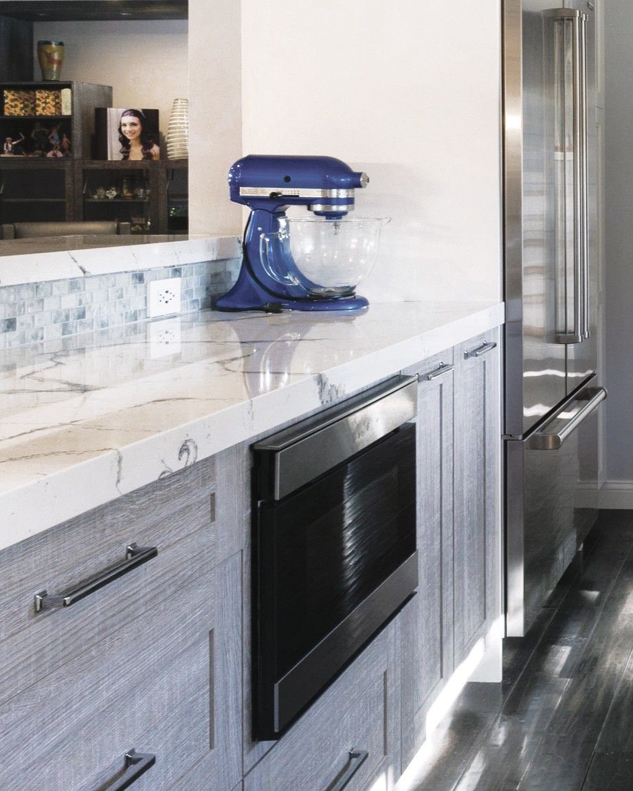 This is a picture of a silver and white kitchen made from cabinetry custom by Kountry Kraft Cabinetry. It focuses on a built in microwave drawer in a base cabinet.