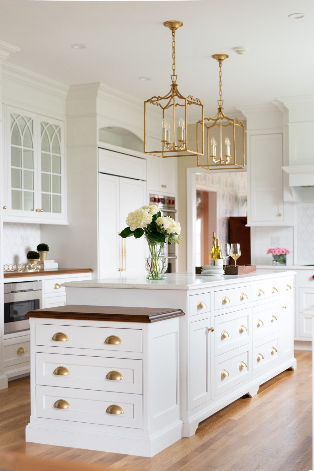 White Kitchen Cabinets New England. Brass hardware. Island dropdown with wood countertop.