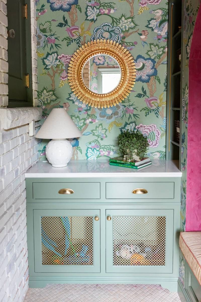 Cabinetry detail with gold sunburst mirror, floral wallpaper, and countertop decor in the Designer Show House mudroom.