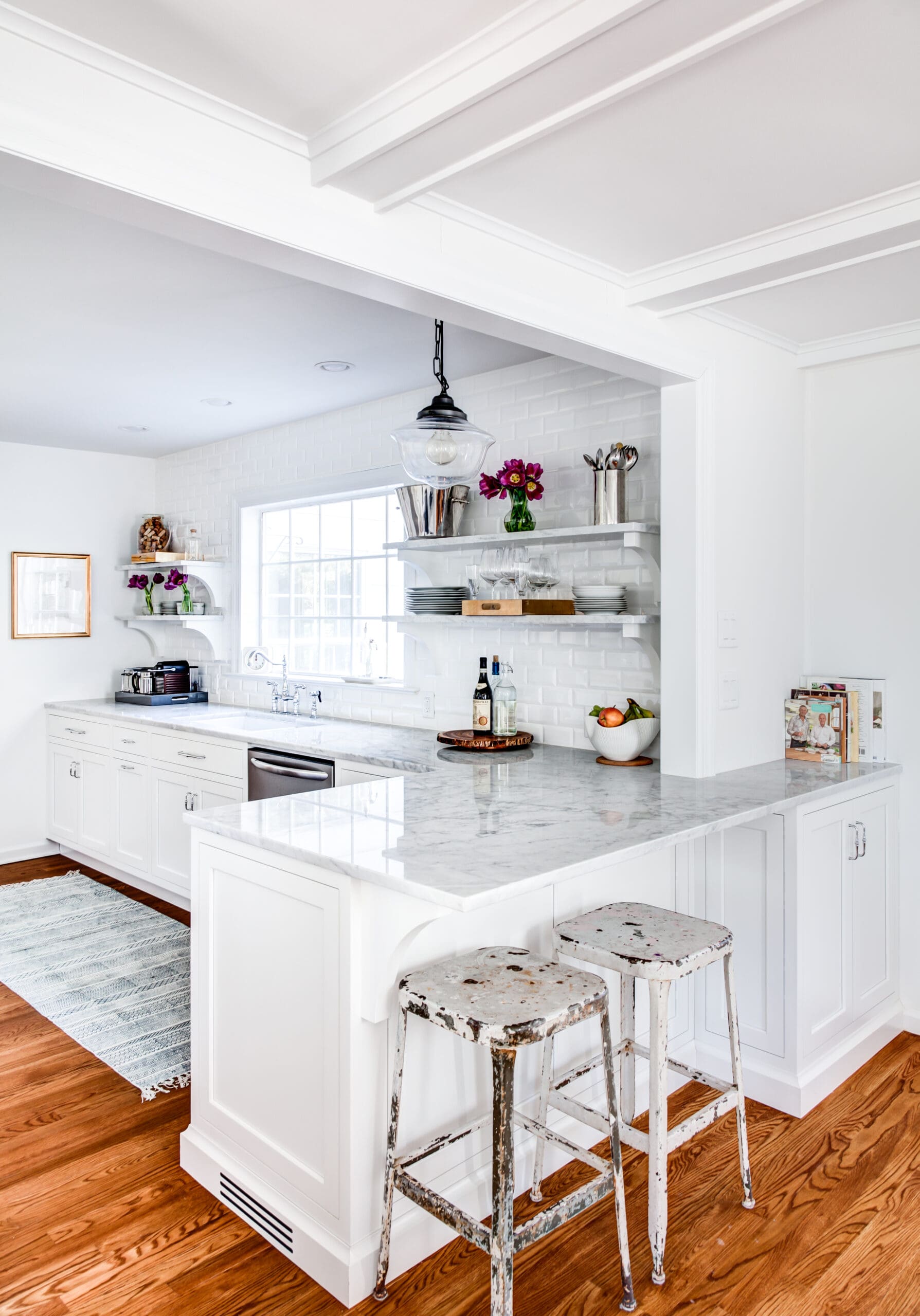 Small kitchen cabinetry. Cabinets are finished in a white paint. Open shelving instead of upper cabients. Peninsula seating for two.