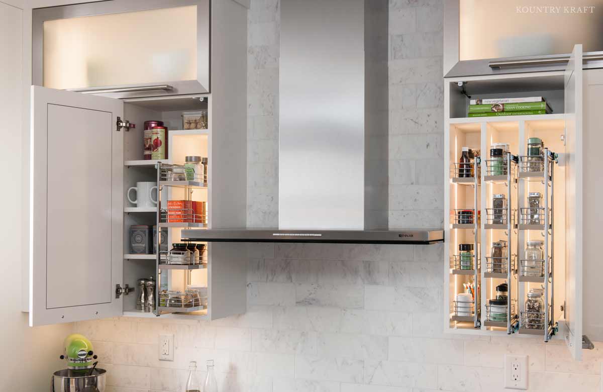 White kitchen cabinetry with doors open showing pull out storage solutions and interior cabinet lighting.