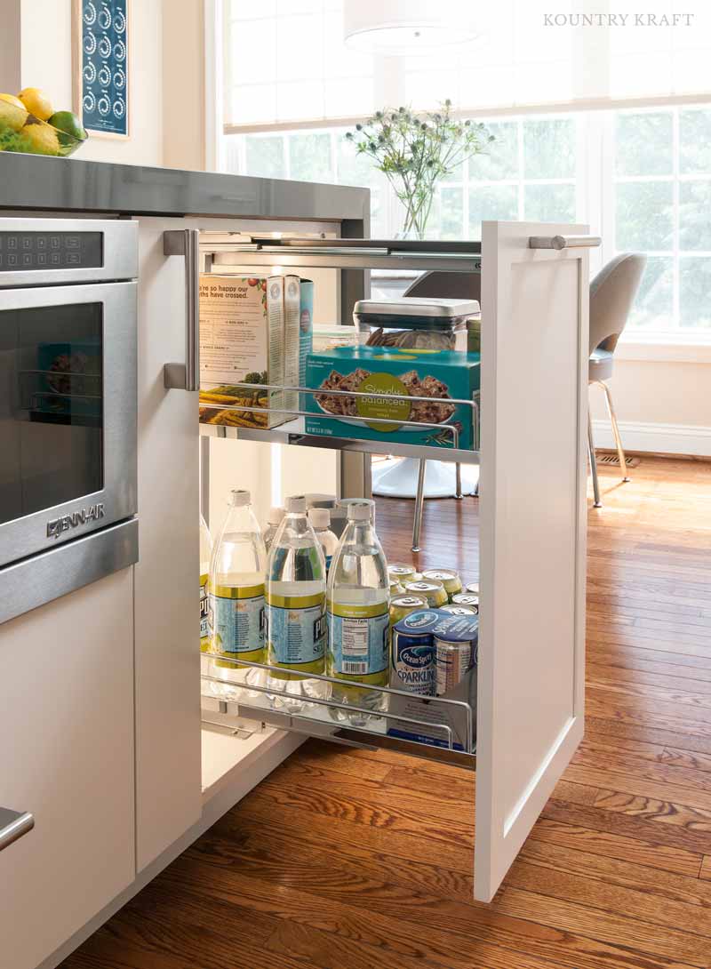 White kitchen cabinetry with base pull out storage solution and in cabinet lighting.