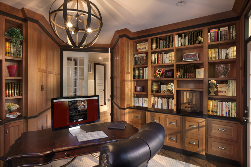 Custom home office built-ins in Pennsylvania with floor-to-ceiling wood bookcases, integrated drawers, and paneled lower cabinetry.