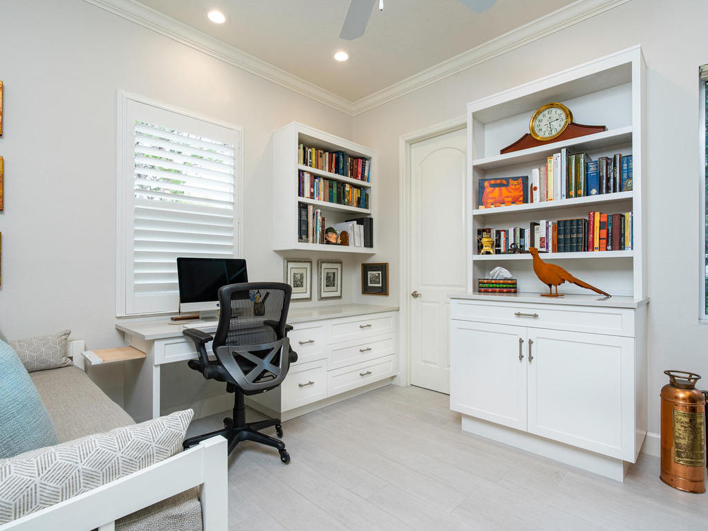 Custom home office cabinets in Venice, FL with a white built-in desk, drawer storage, and open bookcases.