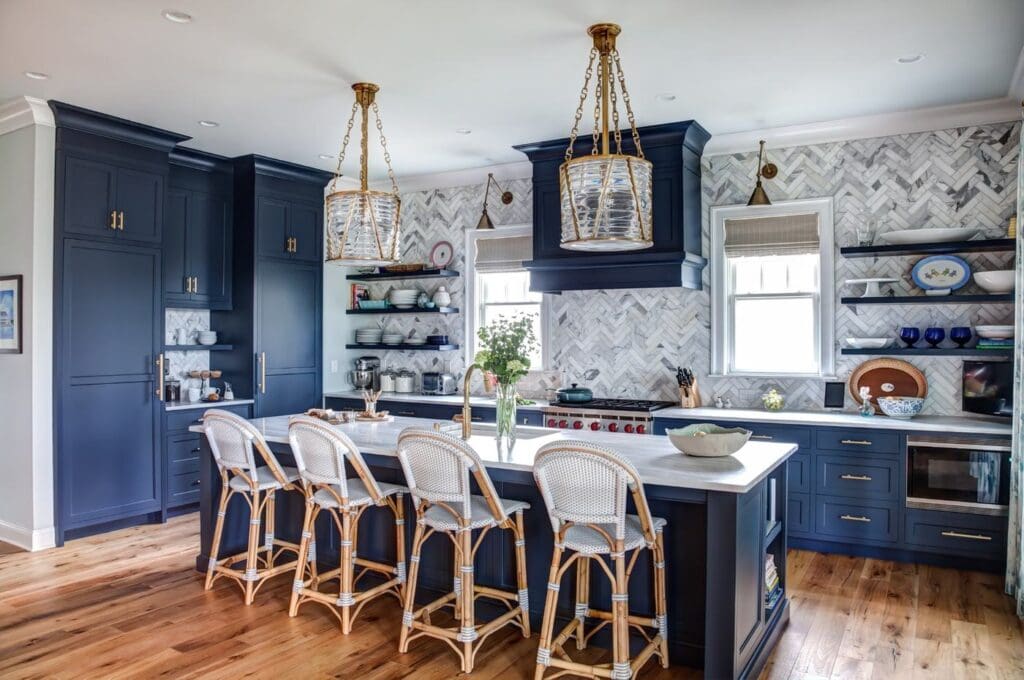 Hale Navy kitchen cabinets and matching range hood with brass hardware and a marble-topped island.